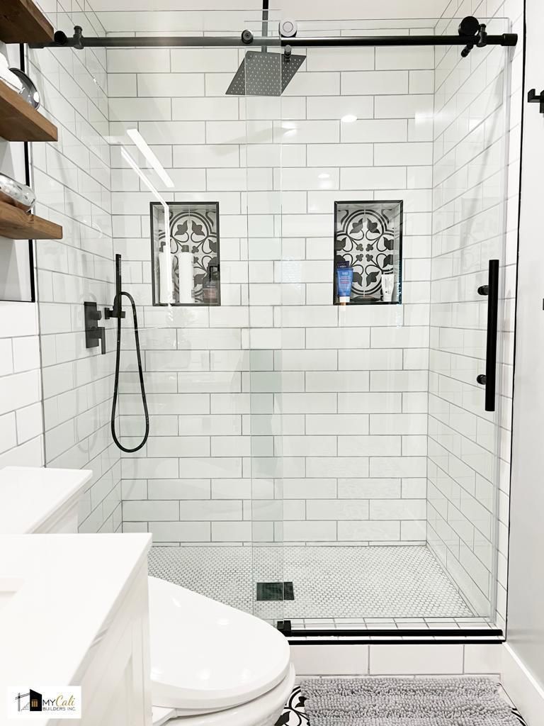 Glass shower enclosure with black fixtures and patterned tiles.